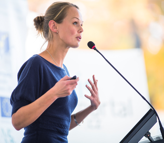 Side image of a female speaker at the podium